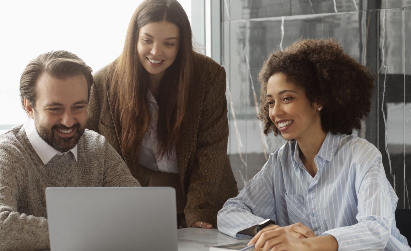 um homem e duas mulheres trabalhando em um notebook