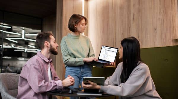 Profissionais em ambiente corporativo analisando documentos digitais em um notebook, representando a gestão documental inteligente e acessível para PMEs da McFile.