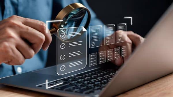 profissional analisando documentos digitais em sistema de compliance com lupa em notebook